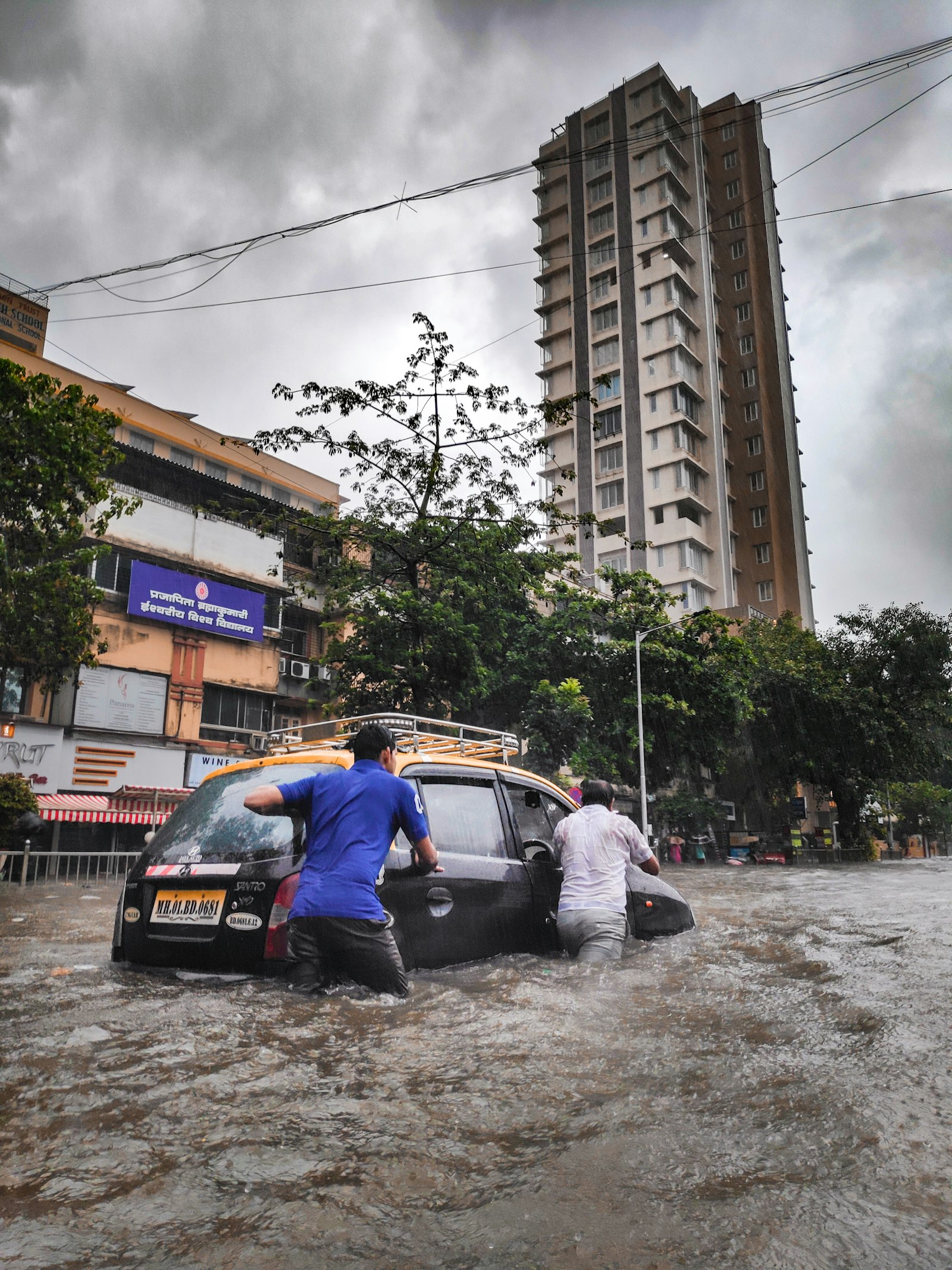 Illustrative image of two men pushing a car through a flooded city street (not Bangkok)