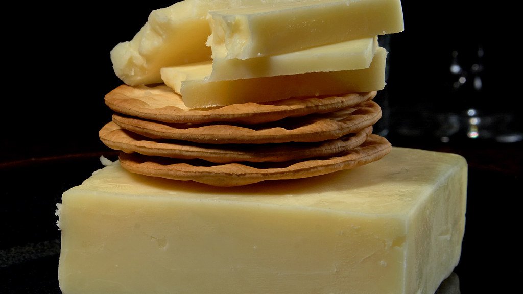 A block of white cheddar with sliced cheese on crackers — illustrative, not the recalled brand