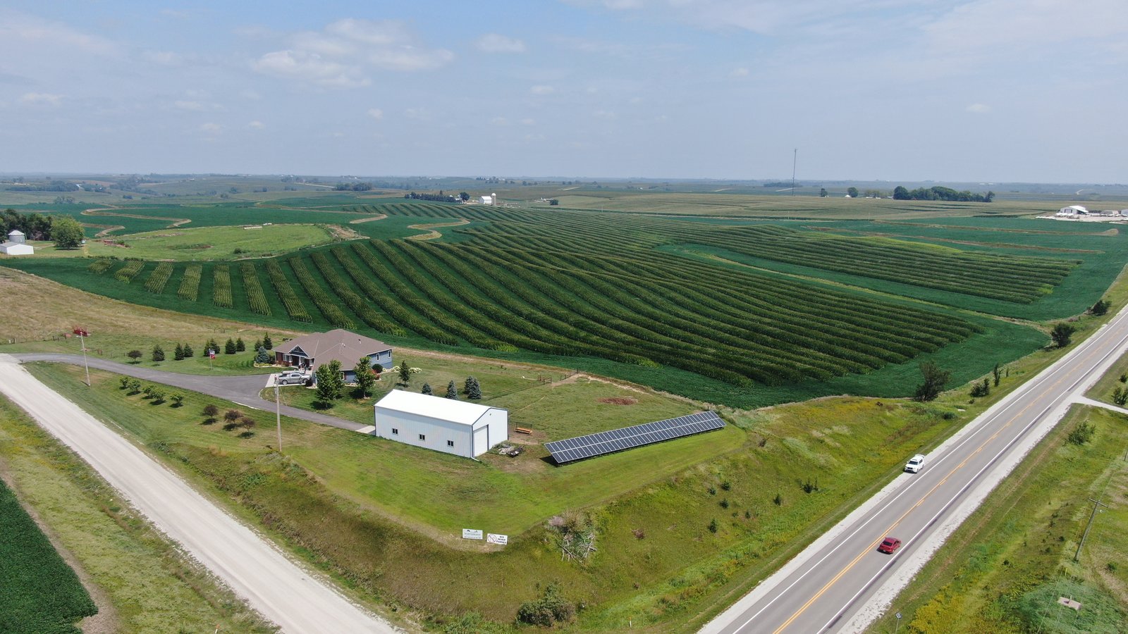 Aerial view of a U.S. farm with a small ground-mounted solar array beside a barn — illustrative