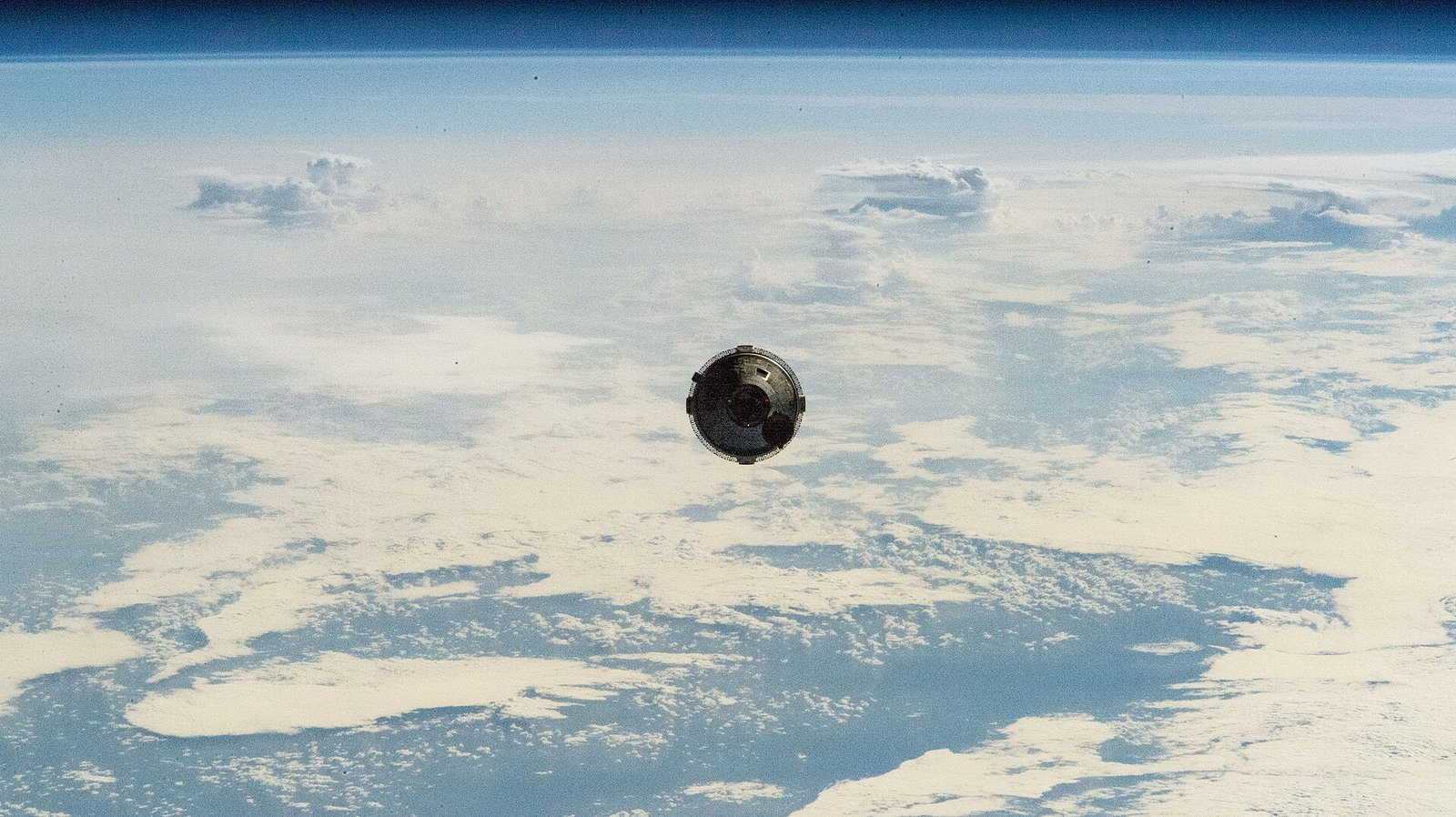 Boeing’s Starliner capsule, photographed from the International Space Station as it approached for docking above a cloud-covered Earth during the June 2024 crewed test flight