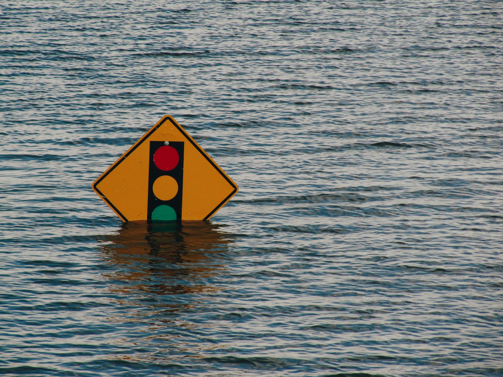 Illustrative image of a traffic-signal warning sign nearly submerged in floodwater