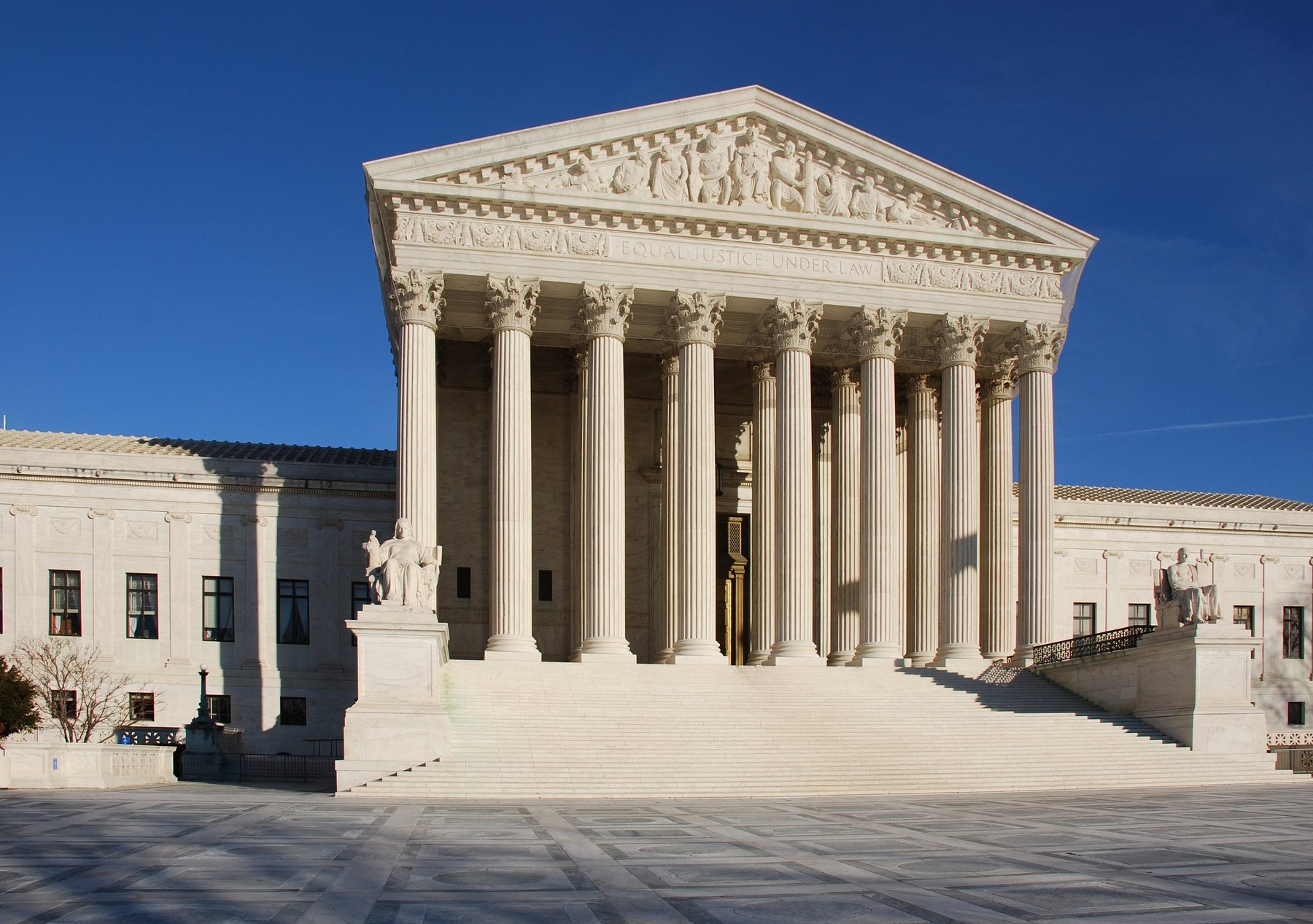 West front of the U.S. Supreme Court building, with marble columns, the “Equal Justice Under Law” frieze and wide front steps under a clear blue sky